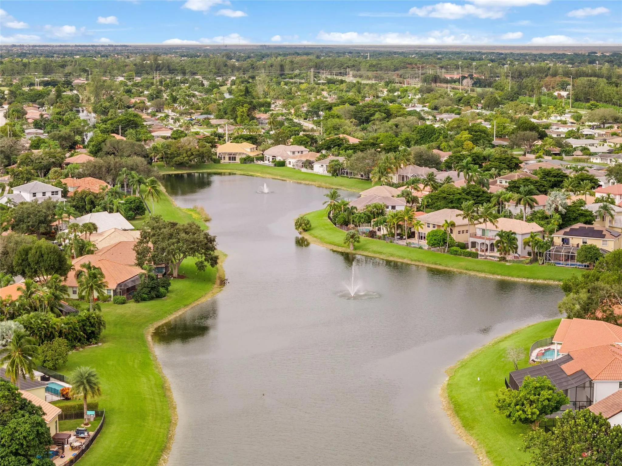 Aerial view of Lexington Estates in Boca Raton, FL featuring single-family homes, private lakes, lush landscaping, and exclusive waterfront homes.